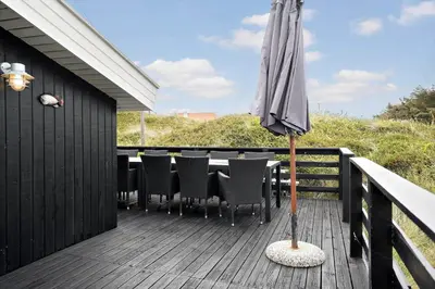 a patio with an umbrella on a wooden deck at 807-Harboore-Dalevej-9 in Harboør