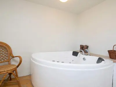 a white bath tub in a room with a chair at 12 person holiday home in Lemvig in Lemvig