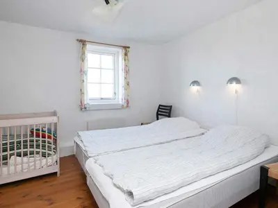 a white bedroom with a crib and a window at 12 person holiday home in Lemvig in Lemvig