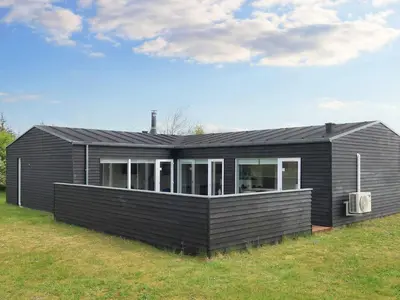 a black house sitting on top of a grass field at Tranquil Retreat in Nature s Embrace-By Traum in Brovst
