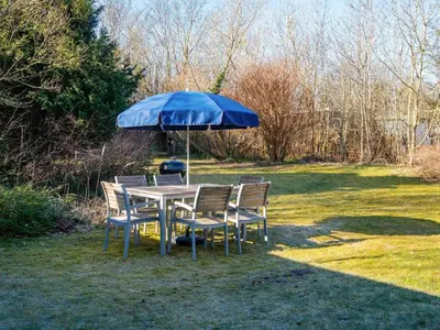 a table and chairs with a blue umbrella at 4 person holiday home in Nibe-By Traum in Nibe