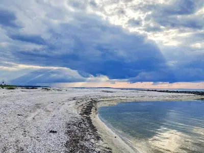 a beach with a cloudy sky and some water at 5 person holiday home in Løgstør in Løgstør