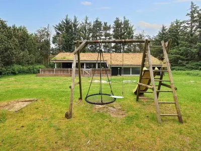 a swing set in a yard with a house at 12 person holiday home in Saltum-By Traum in Saltum