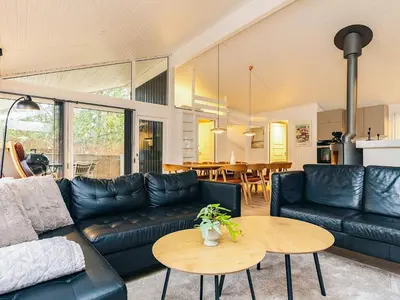 a living room with a black leather couch and a table at 12 person holiday home in Saltum-By Traum in Saltum