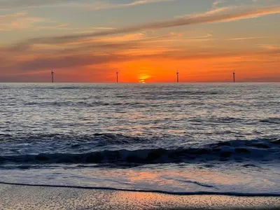 a sunset over the ocean with windmills in the distance at 10 person holiday home in Harboøre-By Traum in Harboør