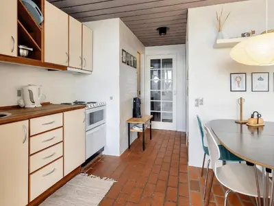 a kitchen with white cabinets and a table with chairs at Seaside Serenity in TAYsinge-By Traum in Brovst