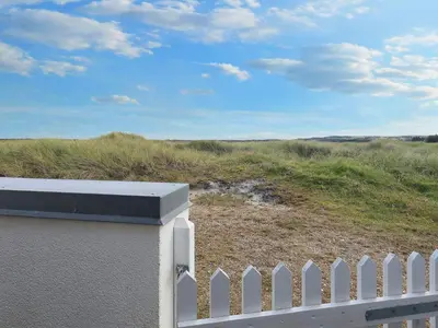 a white picket fence in front of a field at Seaside Serenity in TAYsinge-By Traum in Brovst