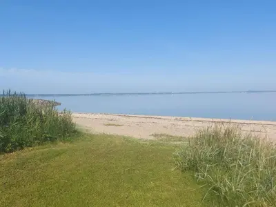 a sandy beach with grass and the ocean in the background at 8 person holiday home in Vinderup-By Traum in Vinderup