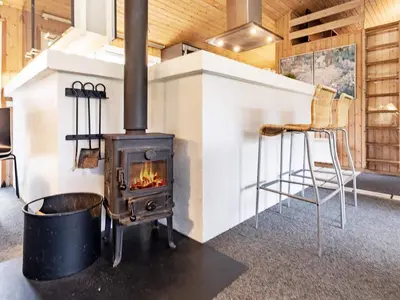 a wood stove in a room with a chair at Luxury Pool House Retreat - By Traum Ferienwohnungen in Saltum