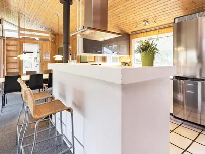 a kitchen with a white counter and some chairs at Luxury Pool House Retreat - By Traum Ferienwohnungen in Saltum