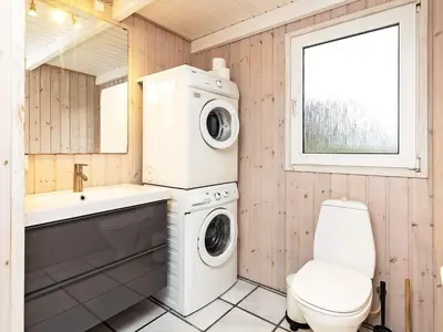 a bathroom with a washing machine and a toilet at Luxury Pool House Retreat - By Traum Ferienwohnungen in Saltum