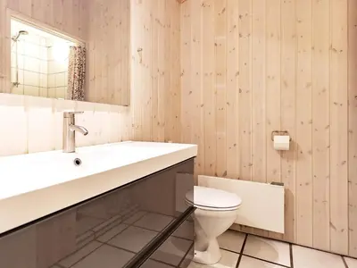 a bathroom with a sink and a toilet at Luxury Pool House Retreat - By Traum Ferienwohnungen in Saltum