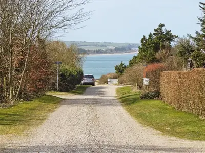 a gravel road with a car parked on the side of a lake at 6 person holiday home in Struer-By Traum in Struer