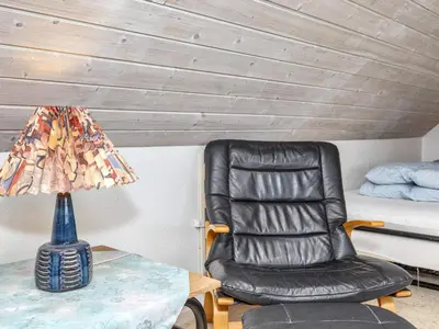 a black leather chair sitting next to a table with a lamp at 6 person holiday home in Thisted-By Traum in Thisted