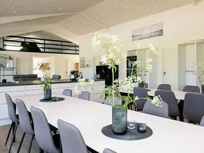 a room with tables and chairs with white flowers on them at 22 person holiday home in Løkken-By Traum in Løkken