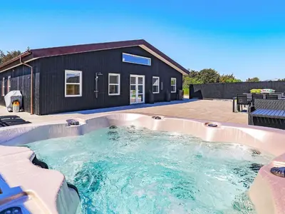 a hot tub in front of a black house at 22 person holiday home in Løkken-By Traum in Løkken
