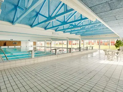 a swimming pool with tables and chairs in a building at 4 person holiday home on a holiday park in Lemvig in Lemvig