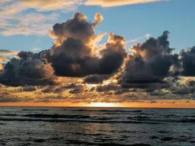 a sunset over the ocean with clouds in the sky at 6 person holiday home in Løkken in Løkken