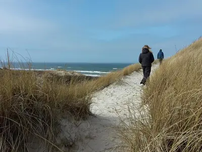 two people walking down a sandy path to the beach at 6 person holiday home in Løkken in Løkken