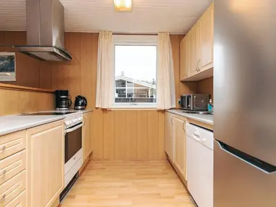 a small kitchen with wooden cabinets and a window at 6 person holiday home in Løkken in Løkken