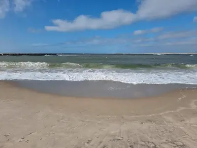 a sandy beach with the ocean and the waves at 10 person holiday home in Harboøre in Harboør
