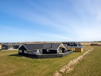 a house with a black roof in a field at 10 person holiday home in Harboøre in Harboør