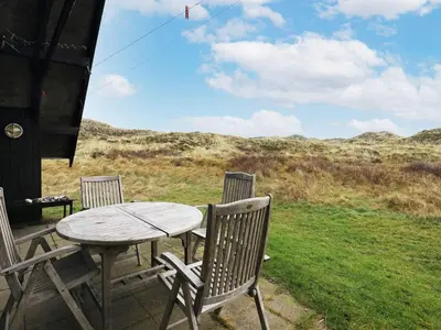 a table and chairs on a porch with a kite in the sky at 6 person holiday home in Pandrup-By Traum in Pandrup