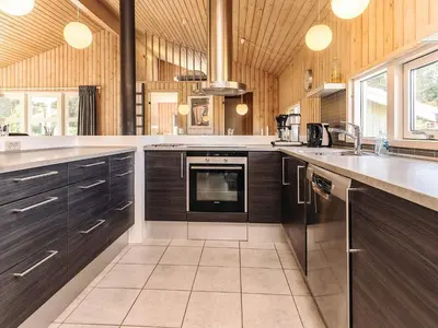 a large kitchen with wooden cabinets and a stove at Luxury Retreat in Klitmoller - By Traum Ferienwohnungen in Thisted