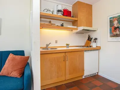 a small kitchen with wooden cabinets and a blue couch at 6 person holiday home in Lemvig-By Traum in Lemvig