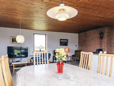 a dining room with a table with flowers in a vase at 7 person holiday home in Frøstrup in Frøstrup