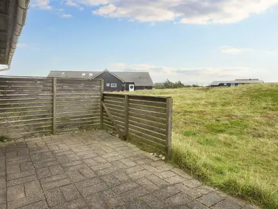 a fence in a field with a house in the background at 5 person holiday home in Harboøre-By Traum in Harboør