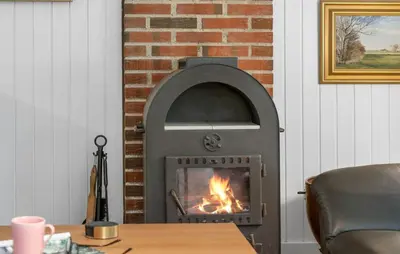 a fireplace in the corner of a living room with a fire at Cozy Home In Vestervig With Sauna in Vestervig