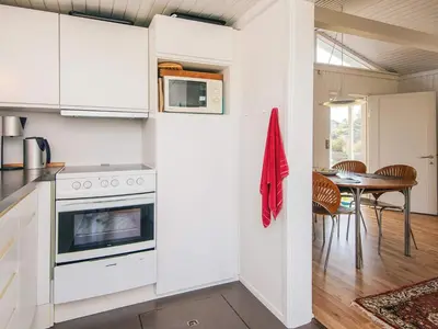 a kitchen with white cabinets and a table with chairs at 4 person holiday home in Blokhus-By Traum in Blokhus