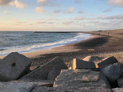 a beach with rocks on the sand and the ocean at 7 person holiday home in Vestervig-By Traum in Vestervig