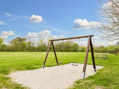 a swing set in a field with a bench at 7 person holiday home in Vestervig-By Traum in Vestervig