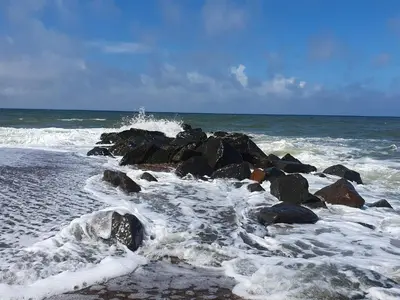 a group of rocks on the beach with waves at 8 person holiday home in Ulfborg-By Traum in Ulfborg