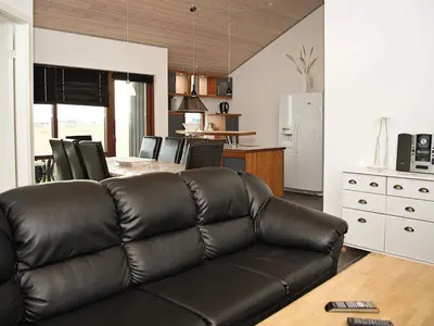 a living room with a leather couch and a kitchen at 8 person holiday home in Ulfborg-By Traum in Ulfborg
