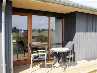 a patio with a table and chairs on a deck at 8 person holiday home in Ulfborg-By Traum in Ulfborg
