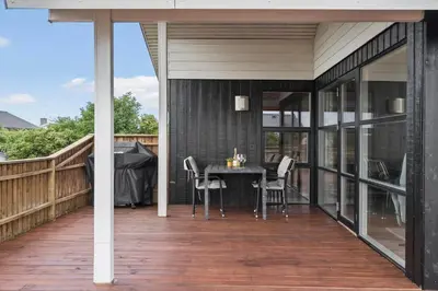 a patio with a table and chairs on a deck at 813-Harboore-Neerlandiavej-136 in Harboør