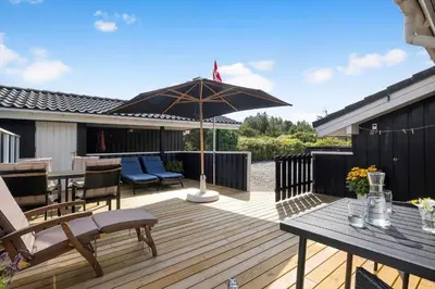 a wooden deck with a table and an umbrella at BL1113-Saltum-Revlingevej-26 in Saltum