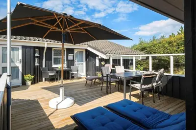 a wooden deck with a table and an umbrella at BL1113-Saltum-Revlingevej-26 in Saltum