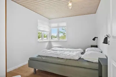 a bedroom with a bed with white sheets and a window at BL1107-Blokhus-Soren-Petersvej-16 in Blokhus