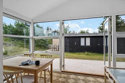 a living room with a table and large windows at BL1107-Blokhus-Soren-Petersvej-16 in Blokhus