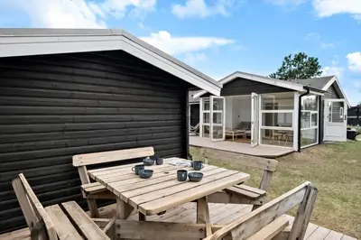 a wooden picnic table in front of a house at BL1107-Blokhus-Soren-Petersvej-16 in Blokhus