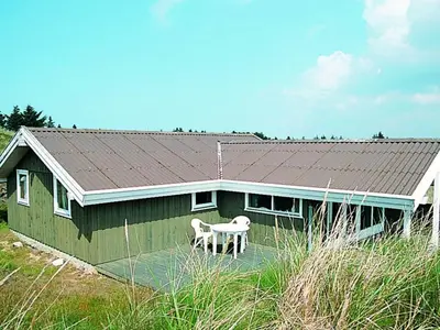 a green house with a white dog sitting in front of it at Spacious Retreat with Views - By Traum Ferienwohnungen in Blokhus