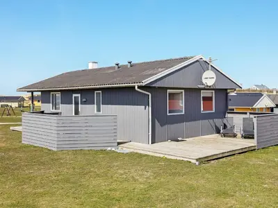 a blue house with a wooden deck in a yard at 6 person holiday home in Lemvig in Lemvig