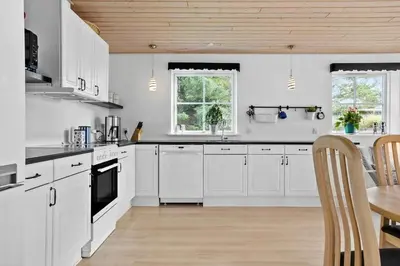 a kitchen with white cabinets and a wooden ceiling at LF14198-Roslev-Bagvejen-2 in Roslev