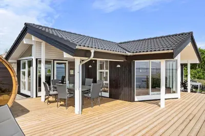 a house with a wooden deck with a table and chairs at LF14194-Roslev-Bagvejen-26 in Roslev