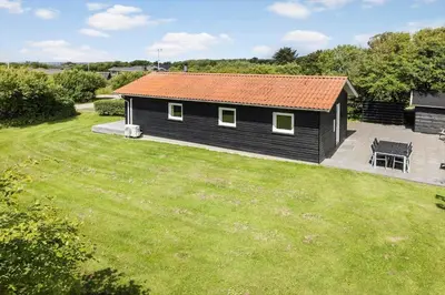 a black house with a red roof in a yard at LF101-Vestervig-Hellesvej-1 in Vestervig