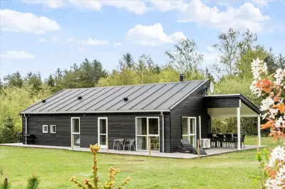 a black house with a porch and a patio at LF15198-Hojslev-Bronzehojen-7 in Højslev